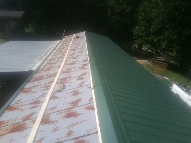 Old rusted panels beside newly installed green metal roofing — Wind Damage Roof Repair by Roofing Brothers in Joseph