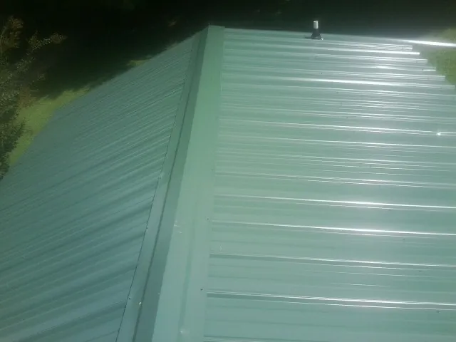 New green metal panels meeting at the ridge of a roof — Flat Roof Repair work by our crew in Joseph