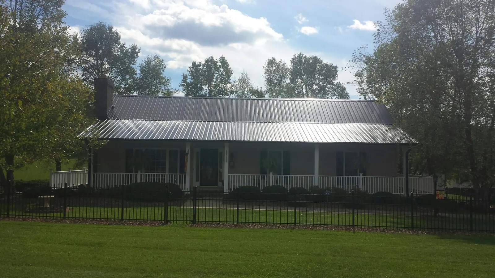 Gray metal roof on a brick ranch with a full width front porch — Gutter Guard Installation work by our crew in Joseph